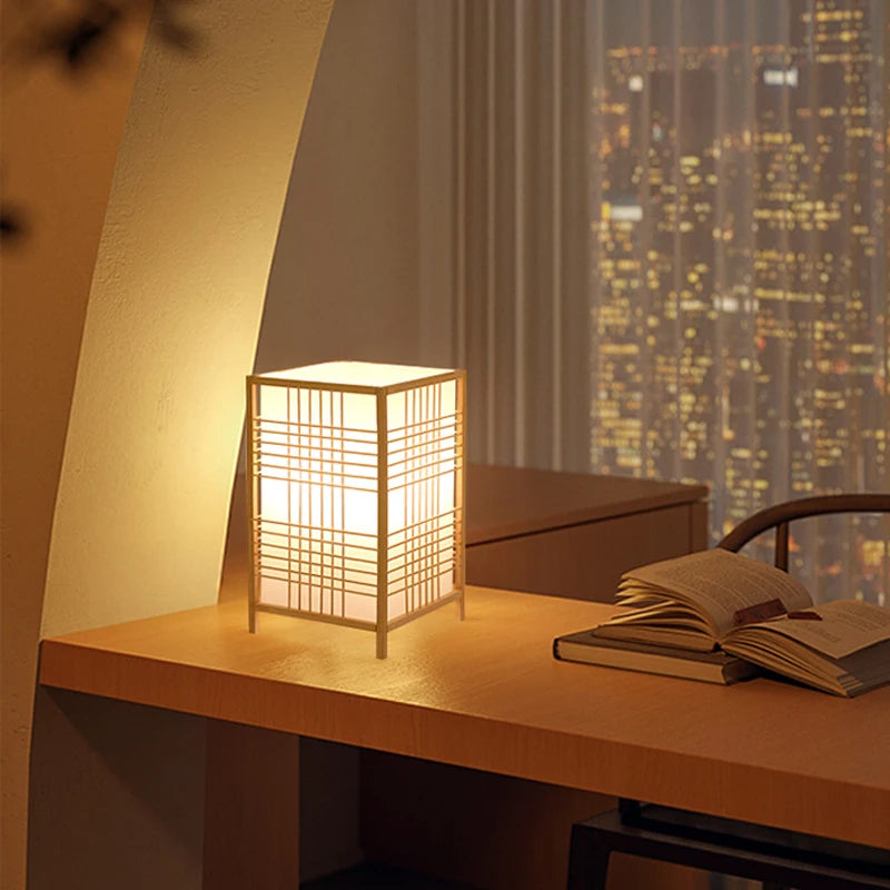 Lampe de bureau design Flora allumée le soir sur un bureau, modèle Croisillon