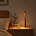 Lampe de bureau design Ambra noire posée sur une table de chevet, ambiance soir