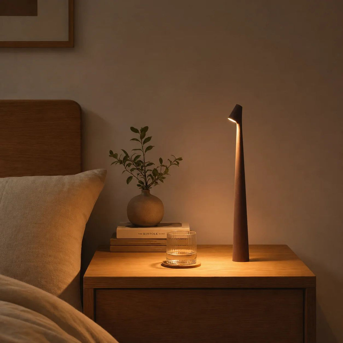 Lampe de bureau design Ambra noire posée sur une table de chevet, ambiance soir