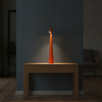 Lampe de bureau design Ambra orange allumée le soir sur une console en bois