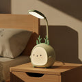 Lampe de bureau enfant Doudou, veilleuse compagnon verte posée sur une table de chevet le jour, bras flexible orienté vers le lit