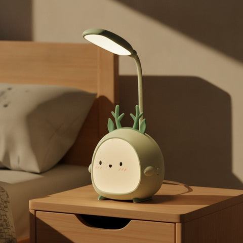 Lampe de bureau enfant Doudou, veilleuse compagnon verte posée sur une table de chevet le jour, bras flexible orienté vers le lit