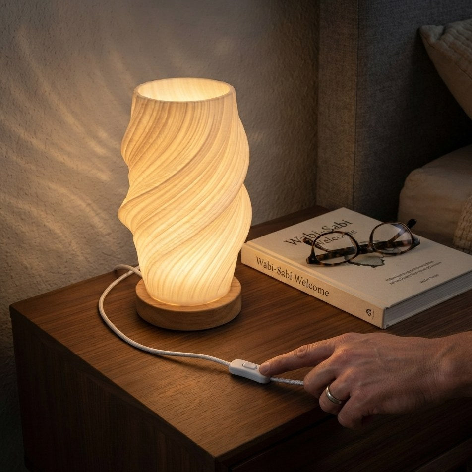 Main réglant la lampe de bureau LED d'ambiance Halo avec la commande sur le câble, sur une table de chevet le soir — Candeora