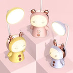 Lampe de bureau enfant Câlin en trois coloris, jaune, rose et violet, lumières allumées, sur des cubes rose pâle