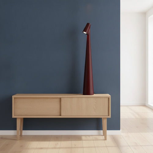 Lampe de bureau design Ambra Candeora coloris bordeaux, posée sur un meuble bas