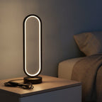Lampe de bureau design Opale allumée le soir sur une table de chevet, anneau lumineux blanc chaud