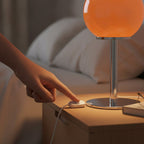 Lampe de bureau design Stellaria, main appuyant sur le boîtier de commande du câble