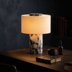 Lampe Vesta en marbre allumée sur un bureau le soir, ambiance feutrée