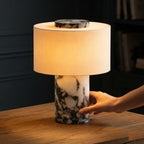 Main réglant la lampe Vesta en marbre à sa base, lumière chaude