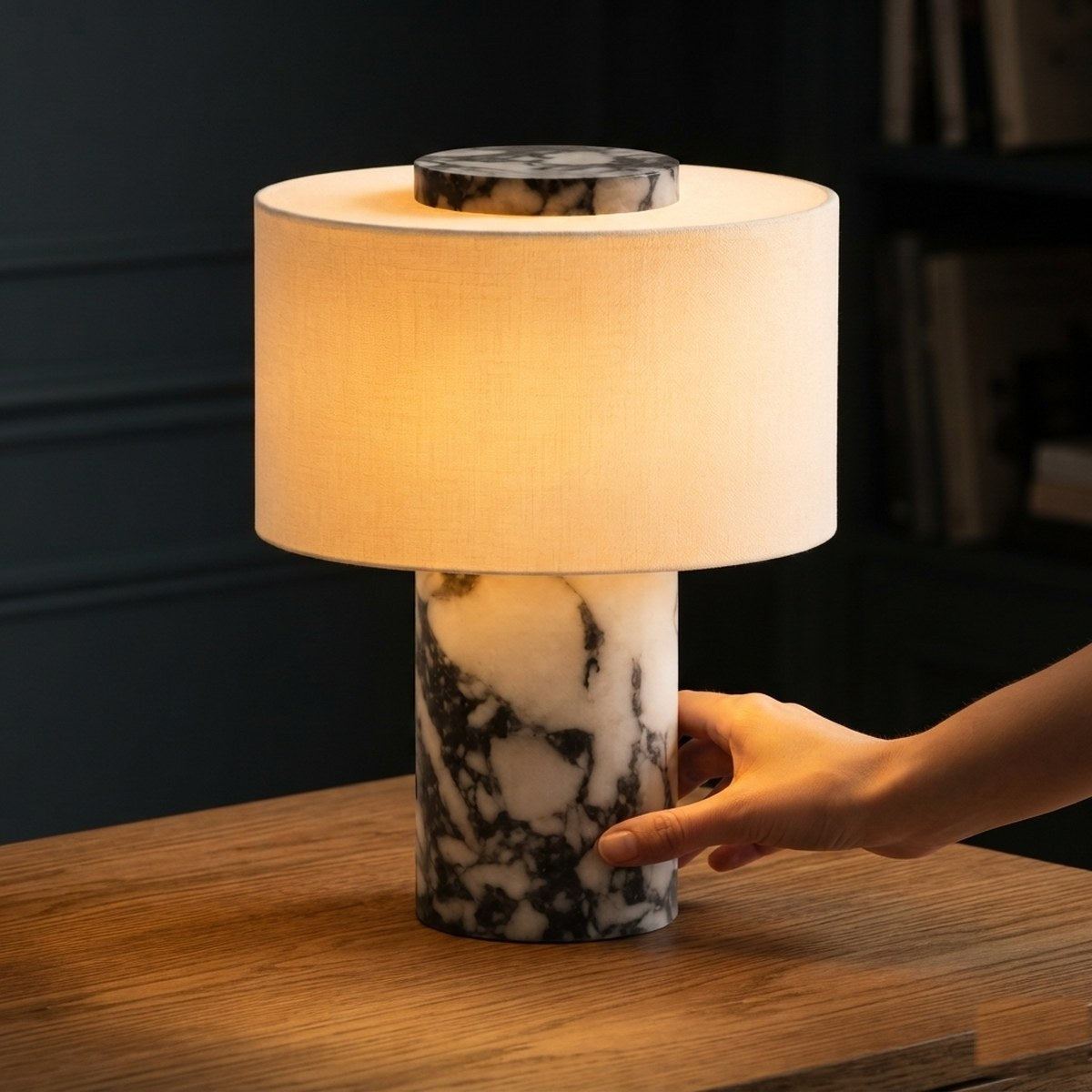 Main réglant la lampe Vesta en marbre à sa base, lumière chaude