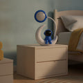 Lampe de bureau enfant Astro Candeora, astronaute bleu sur croissant de lune, sur une table de chevet