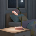 Lampe de bureau enfant Fleurette allumée sur une table de nuit, le soir
