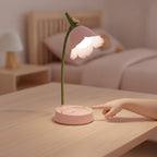 Main d'enfant qui touche la zone tactile du socle de la lampe de bureau enfant Fleurette allumée