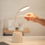 Main réglant le bras flexible de la lampe de bureau LED Andromède