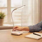 Main orientant le col flexible de la lampe de bureau LED Cassiopée sur un bureau en bois