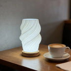Lampe d'ambiance Halo allumée sur une table en bois foncé, à côté d'une tasse de café — Candeora