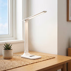 Lampe de bureau LED pliable Aube en lumière blanche sur un bureau en chêne, en journée