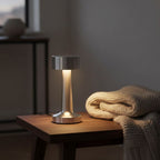 Lampe de bureau sans fil Bora allumée le soir sur une table basse