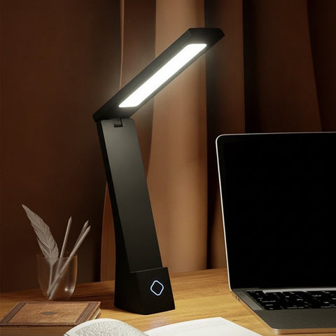Lampe de bureau sans fil pliable Brise Candeora en finition noire, allumée sur un bureau