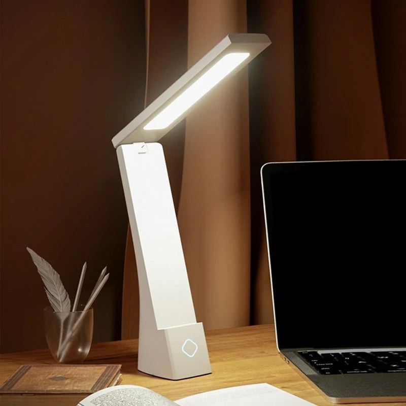 Lampe de bureau sans fil Brise Candeora allumée sur un bureau, à côté d'un ordinateur portable