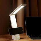 Téléphone posé dans le pli de la lampe de bureau Brise Candeora, qui lui sert de support