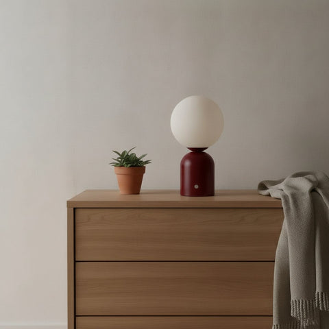 Lampe de bureau sans fil Foehn Candeora coloris rouge, globe opalin, posée sur une commode