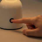 Main effleurant le bouton tactile du socle de la lampe de bureau sans fil Foehn