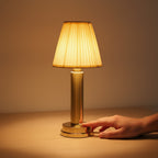 Main qui allume la lampe de bureau sans fil Ponant en touchant sa base dorée