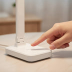 Main effleurant la commande tactile de la lampe de bureau sans fil Suroît blanche - Candeora