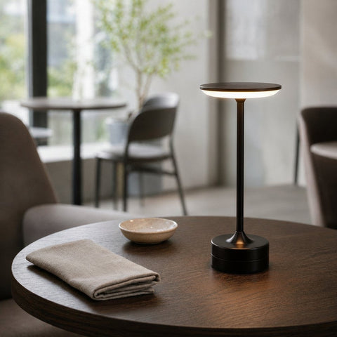 Lampe de bureau sans fil Zéphyr Candeora en finition noire, allumée sur une table ronde