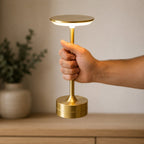 Main portant la lampe sans fil Zéphyr par sa colonne, allumée — Candeora
