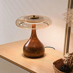 Lampe de bureau design Lucerna en bois et disque de verre, allumée sur un bureau, lumière chaude.