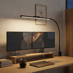 Lampe de bureau LED Orion éclairant un double écran en lumière chaude, le soir